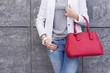© visoook - Casual woman in white jacket with red bag in hand street look