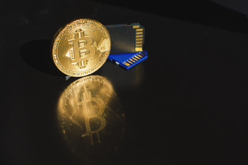 Gold bitcoin cryptocurrency coin with flash cards on a black background with reflection