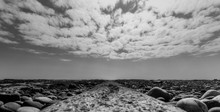 Scottish Landscape Of A Beach With Pebbles And Sea Weed In Black And White With A Cloudy Sky