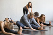 © fizkes - Group of young sporty people practicing yoga lesson with instructor, sitting in Janu Sirsasana exercise, Head to Knee Forward Bend pose, working out, indoor, studio. Wellbeing, wellness concept
