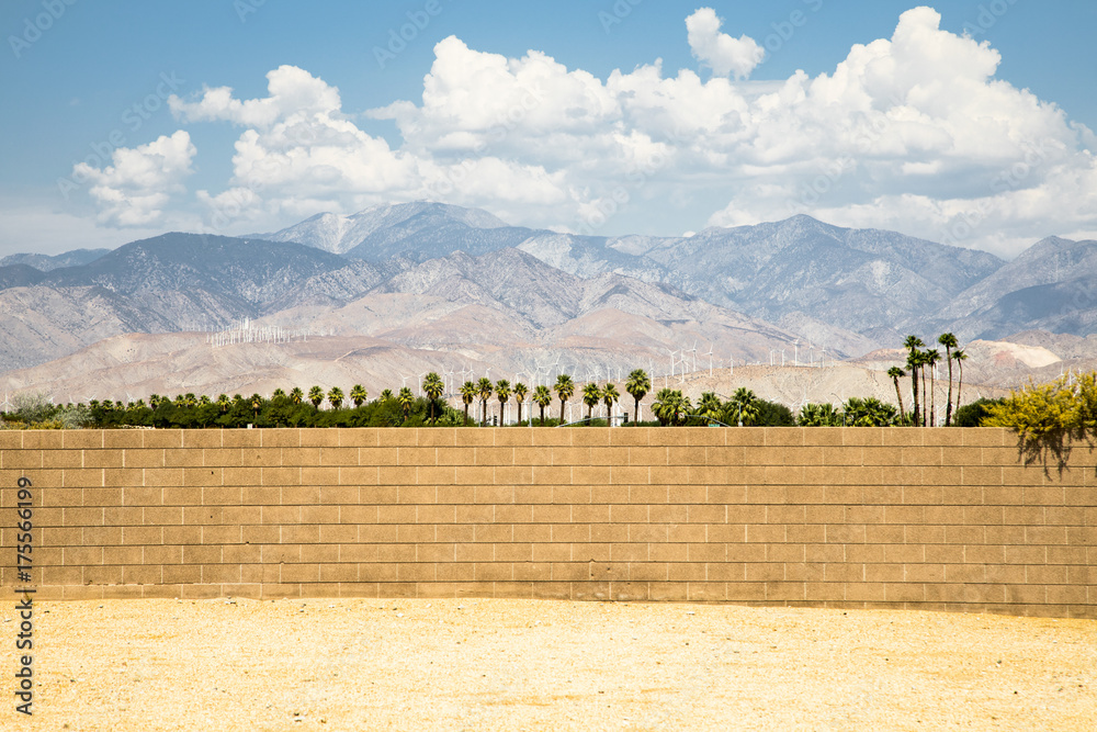 Looking beyond a brick wall in Palm Springs with the famous wind turbines in the background - obrazy, fototapety, plakaty 