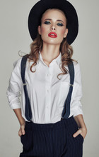 Fashion Woman Standing On A Gray Background, With A Black Hat And A Man's Shirt. Vintage Concept.