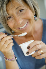 Wall Mural - Portrait of senior woman eating yoghurt