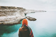 Woman looking at cold sea view alone Travel Lifestyle concept adventure vacations outdoor. Girl wearing fashion orange knitted hat and scarf. Melancholy solitude emotions