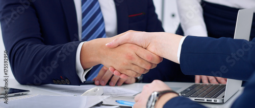 Zdjęcie XXL Biznesowy uścisk dłoni przy spotkaniem lub negocjacją w biurze, zakończenie. Partnerzy są zadowoleni, ponieważ podpisują umowę lub dokumenty finansowe