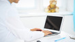 © rogerphoto - Woman doctor using laptop computer while standing straight in hospital