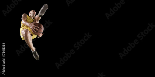 Zdjęcie XXL Gracz koszykówki robi slam dunk. Odosobniony gracz koszykówki na czarnym tle. Gracz nosi ubrania niemarkowe.