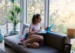 © Carolyn Lagattuta/Stocksy - Teenage girl on the couch in a modern home looking at the laptop