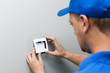electrician in blue uniform installing light switch on the wall