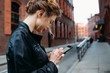 © michela ravasio/Stocksy - Young woman texting in street
