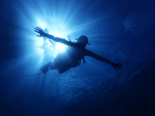 Person Swimming Underwater With Sun Rays Behind