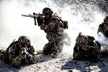 Team Squad Of Special Forces In Action In The Desert Among The Rocks Covered By Smoke Screen