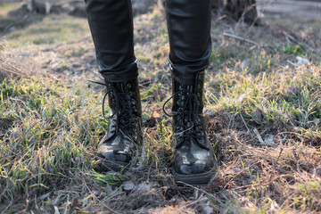   A pair of Leather Shiny Boots in the forest. Girl in big boots. Decorative background for shoes industry.