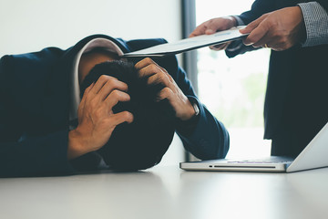 Wall Mural - Angry boss giving a document to a sad employee sitting in a desk at office