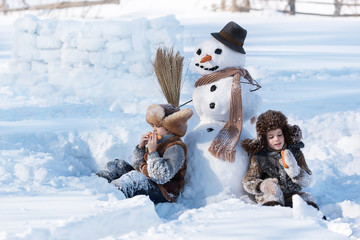 Wall Mural - Children shape the snowman in the backyard of the house