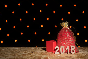 Wall Mural - Red New Year's bag with a gift, box and figures 2018 on a background with an orange garland