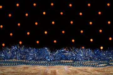 Wall Mural - Blue New Year's tinsel and beads on a wooden table on a background with an orange garland