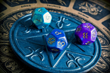 dice with astrology symbols lying on magic pentagram and background with zodiac signs