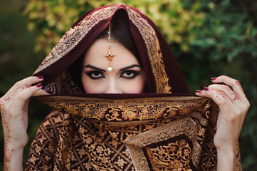 Portrait of beautiful indian girl . Young hindu woman model with tatoo mehndi and kundan jewelry.