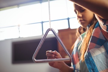 Wall Mural - Low angle view of girl playing triangle