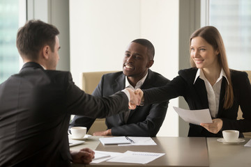 Wall Mural - Smiling businesswoman handshaking with partner at beginning of multinational negotiations. Afro american entrepreneur with female secretary introducing themselves on meeting with caucasian colleague