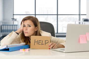 attractive sad and desperate business woman suffering stress at office laptop computer desk holding help sign