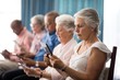 Row of senior people sitting on chairs using digital tablets