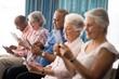 © WavebreakMediaMicro - Smiling senior people using digital tablets while sitting on