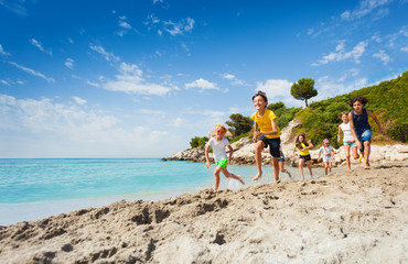 Kids run on the beach at summer hot day