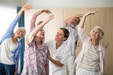 Wall Mural - Smiling female doctor assisting senior woman exercising