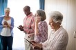 © WavebreakMediaMicro - Seniors using technologies while standing against window