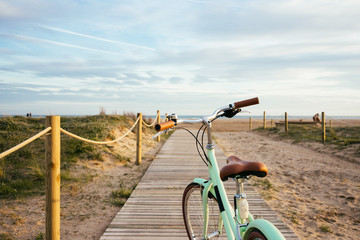 Lonely beautiful mint bike on wooden boardwalk to sea with soft sunset