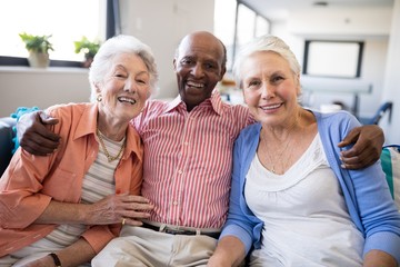 Wall Mural - Portrait of senior man sitting with arm around over females