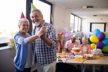 Wall Mural - Portrait of smiling senior couple holding hands at party