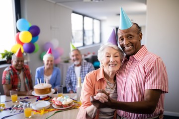 Portrait of senior couple wearing party hats standing by table