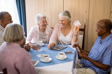 Wall Mural - Happy senior people enjoying tea while playing cards