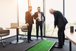 © VadimGuzhva - A respectable elderly man is playing golf in his office. Next to him are his workers. They look like the boss is playing
