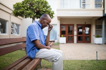 Sad senior man sitting on wooden bench