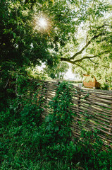 Wattle in the green garden. Small Fence made of weaving thin branches