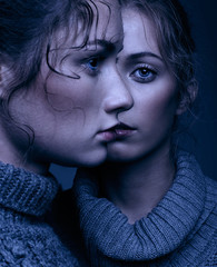 Halloween beauty portrait of two young women in gray sweaters on grey background. Beautiful girls stretching hands forward in embrace. Female friendship concept