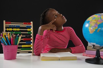 Schoolgirl reading book against black background