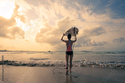 Plakat Tylni widok młoda kobieta surfingowiec z białym surfboard odprowadzeniem morze