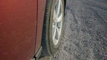 Vehicle Tire Drive On Loose Gravel With Audio. An Exterior Tire Shot Of A Red Vehicle Driving Through Loose Stone And Gravel, With Audio
