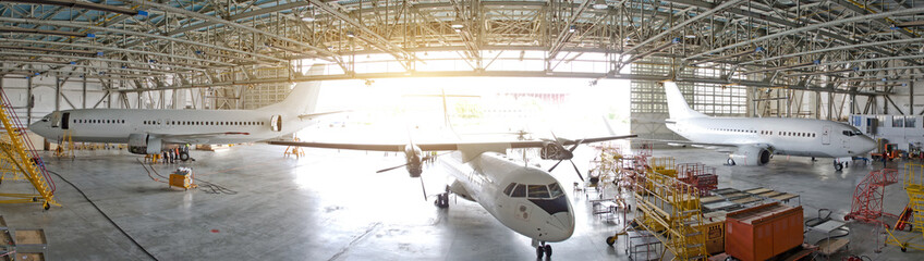 Wall Mural - Three passenger aircraft in a hangar with an open gate for service, view of the panorama.