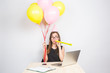 © satura_ - Funny young woman celebrating the success of her business or a birthday in the office holding colorful party balloons