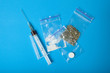 A syringe and a set of illegal drugs in doses on a blue background.
