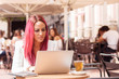© LN_V - Young woman concentrated using a laptop at a table outside a cafe