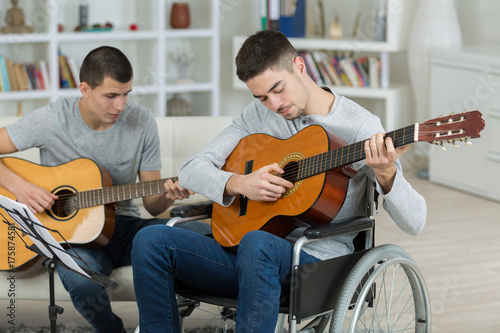 Plakat Młodzi mężczyźni grają na gitarze, jeden na wózku inwalidzkim