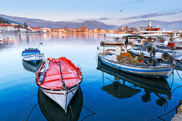 Wall Mural - Breathtaking evening scenery in Kavala sea port, famous and popular resort in northern part of Greece. View over coastline, anchored fishing boats against seascape beneath epic sunset sky.