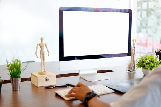 Creative businessman drawing on graphic tablet while using modern desktop computer in office. Blank screen for graphic display montage.
